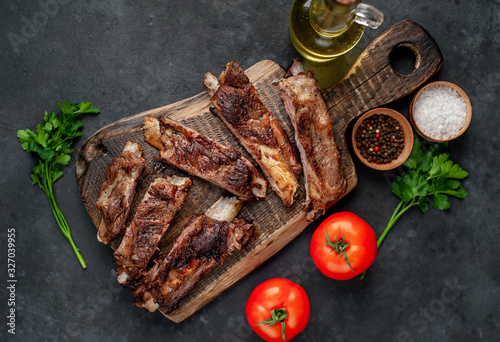 pork ribs with spices, tomatoes and herbs on a stone background
