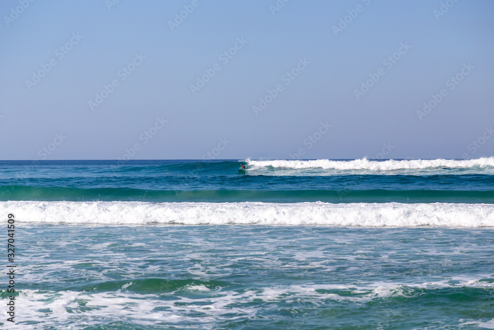 small waves rolling in late in the afternoon with one surfer riding a wave small waves rolling in late in the afternoon with one surfer riding a wave