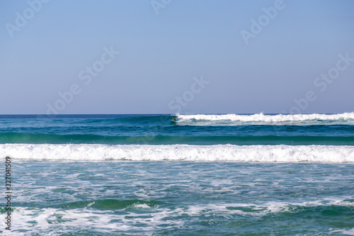 small waves rolling in late in the afternoon with one surfer riding a wave