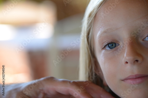 Beautiful little girl with long blond hair and big blue eyes, half face