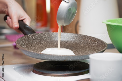 Woman is cooking a pancakes on a frying pan close up.