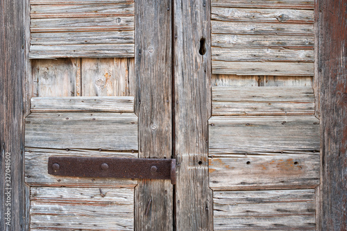 Full frame close-up of pair of rustic weathered wood doors with rusted iron latch