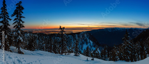 Canadian Nature Landscape covered in fresh white Snow during colorful and vibrant winter sunset with city in background. Taken in Seymour Mountain, North Vancouver, British Columbia, Canada. Panorama