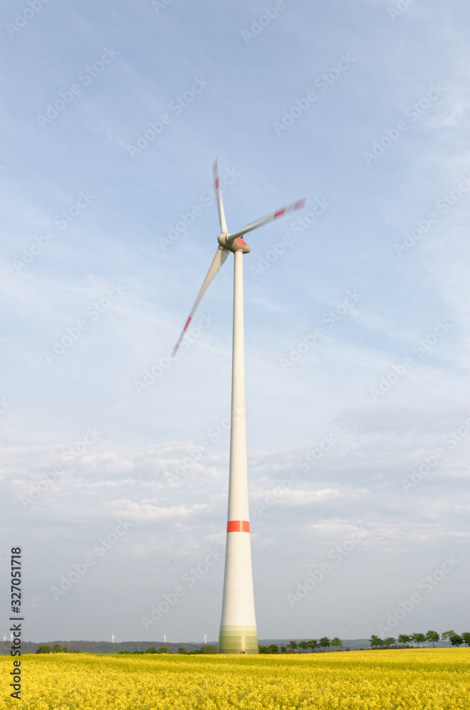 wind turbine on a rapeseed field with wings in motion wind turbine on a rapeseed field with wings in motion
