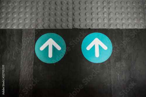 White and Blue Color Arrow Sign as Direction Symbol placed on Floor