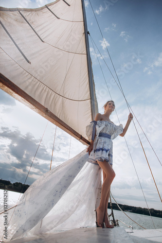 ?oung girl stands on a yacht with white sails in a flying dress. photo