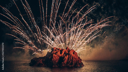  Fireworks over the sea at night with a rock as the protagonist