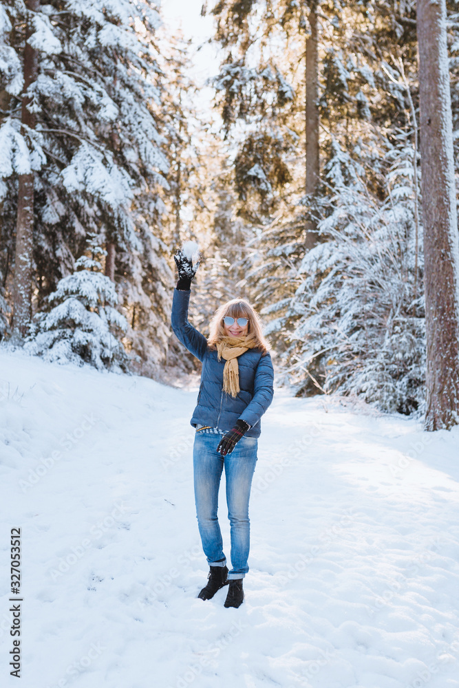 Pretty blonde woman enjoying the snowy mountains - playing snowball in winter