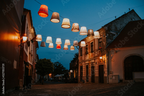 Beautiful evening view of the streets of Szentendre in Hungary. People stroll around at dusk. Lampions from the Art project light up as lanterns.