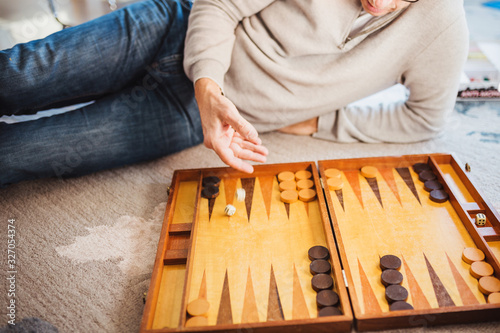 Billede på lærred A man plays backgammon lying on the floor - rolls dice