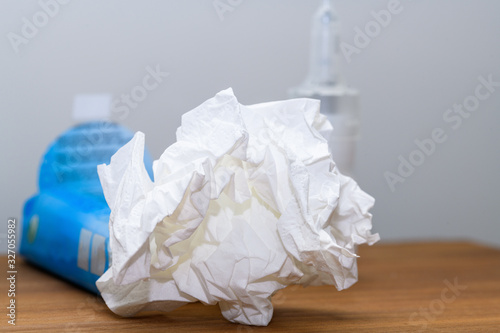Close-up of paper tissue and nasal spray on a nightstand used during cold, flu or virus. Concept for medical conditions such as annual cold, flu or virus indection to cure at home.