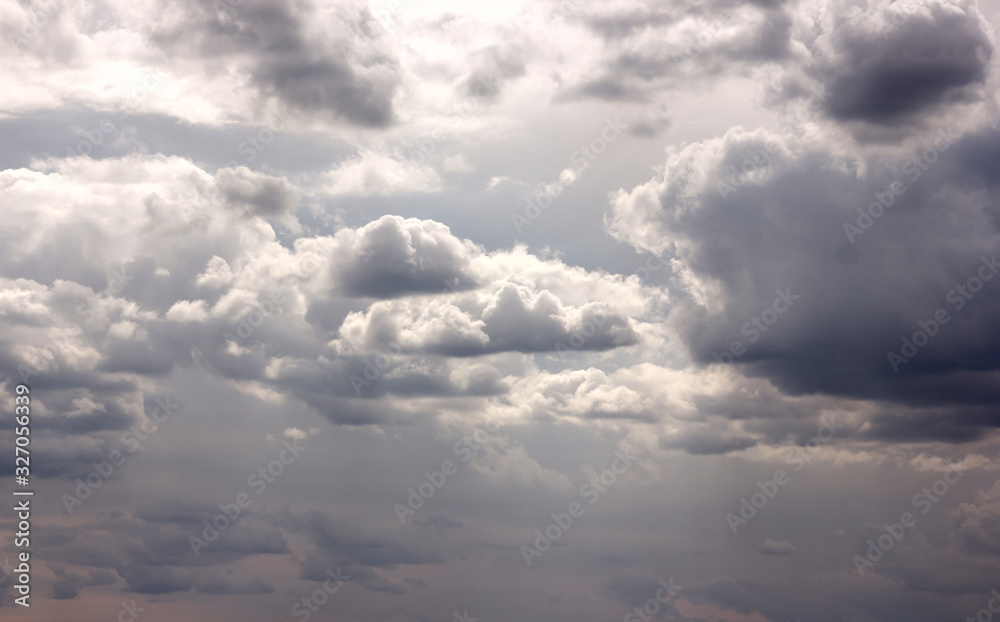 huge cumulus rain clouds and clouds in the sky in the sunshine above the field