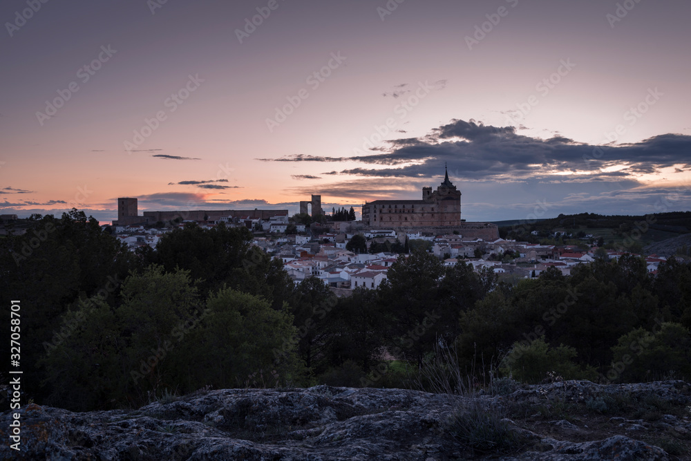 Cityscape of the village of Uclés with the monastery and castle on top of the hill at sunset, Cuenca, Castilla La Mancha, Spain