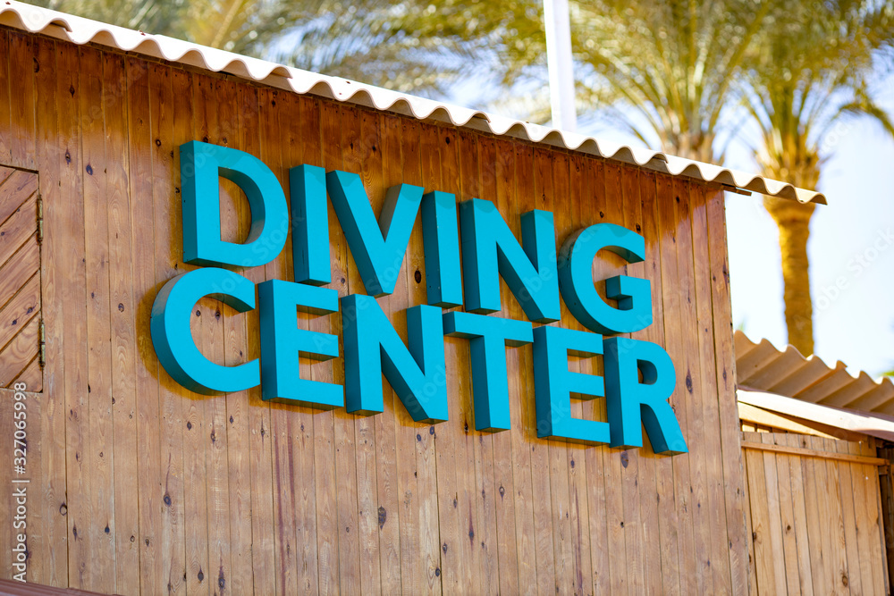 The inscription DIVING CENTER close-up on a wooden building on a background of palm trees