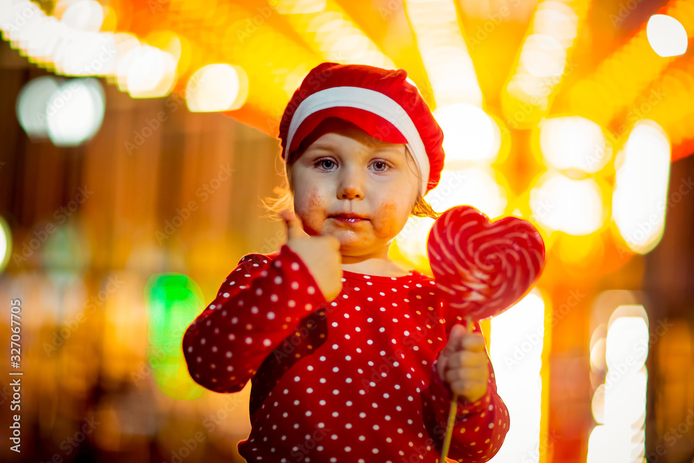 Little girl in red clothes and cap eats candy