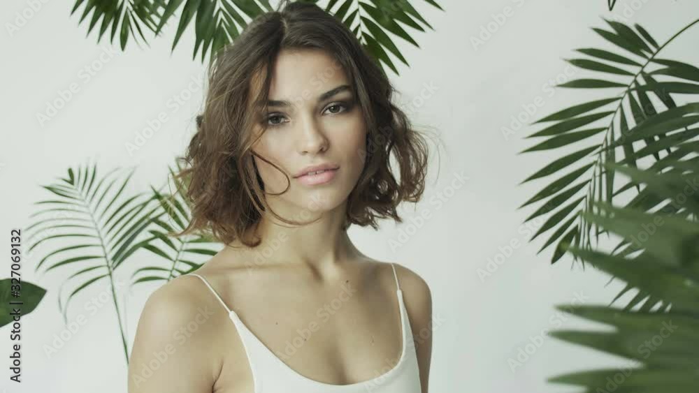 Tanned girl among tropical plants. Palm leaves. Perfect skin. Natural cosmetics. Skin care.