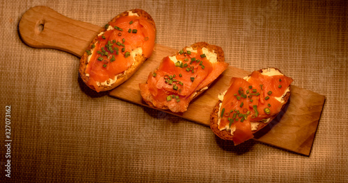 Whole toast with cheese spread and smoked salmon on wooden board