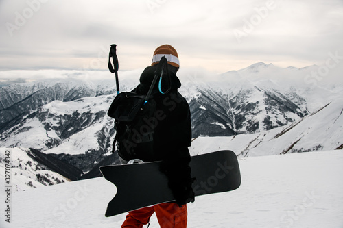 Guy in winter sportswear with snowboard on mountain top photo