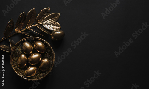  Golden eggs in nest on dark black background.A background for celebrating Easter Top view and copy space Flatlay. Luxury background and Minimal black trend 2020.