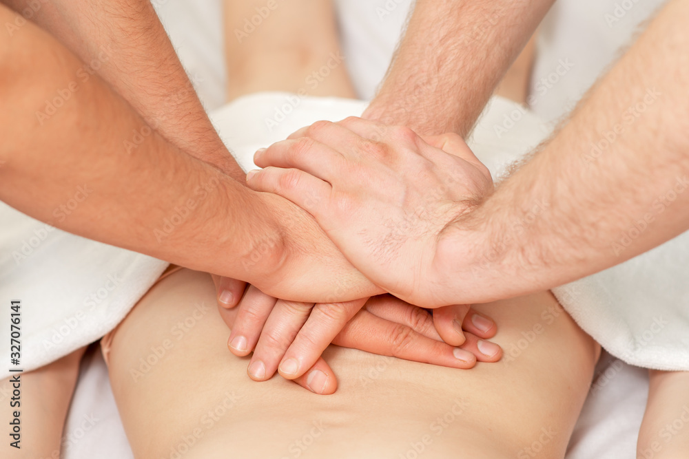 Obraz premium Two male masseuses doing a massage with four hands for woman close up.
