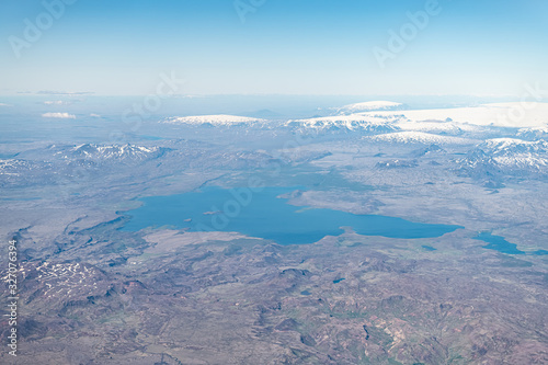 Iceland bird's eye aerial high angle view of Thingvallavatn rift valley lake from airplane window above and snowcapped mountains