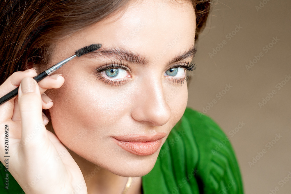 Closeup beautiful woman with eyebrow brush tool, makeup artist combs eyebrows close up. Closeup beautiful woman with eyebrow brush tool, makeup artist combs eyebrows close up.