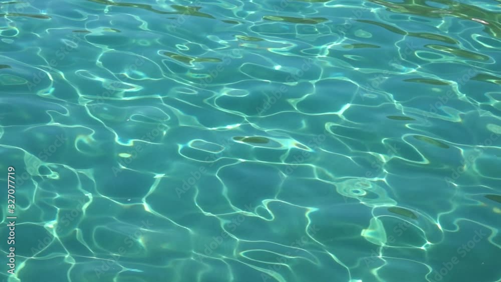 Turquoise sea with clear water, sand and small fish are visible at the bottom. Slow motion. Close up Turquoise sea with clear water, sand and small fish are visible at the bottom. Slow motion. Close up