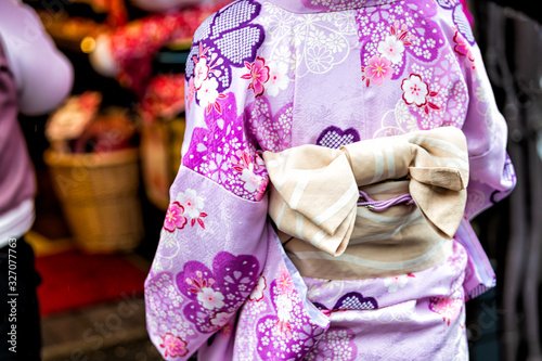 Kyoto, Japan closeup of unrecognizable woman in purple kimono with cherry blossom spring pink pattern and tied bow obi belt © Andriy Blokhin