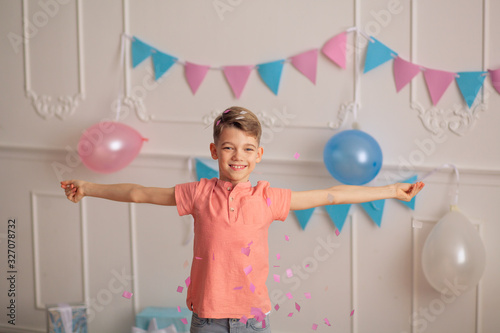 Happy Birthday Portrait of a happy cute boy of 8-9 years old in a festive decor with confetti and gifts.