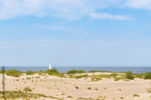 A lonely sailboat on a calm sea seen from a sandy beach © Krzysztof Stasiak