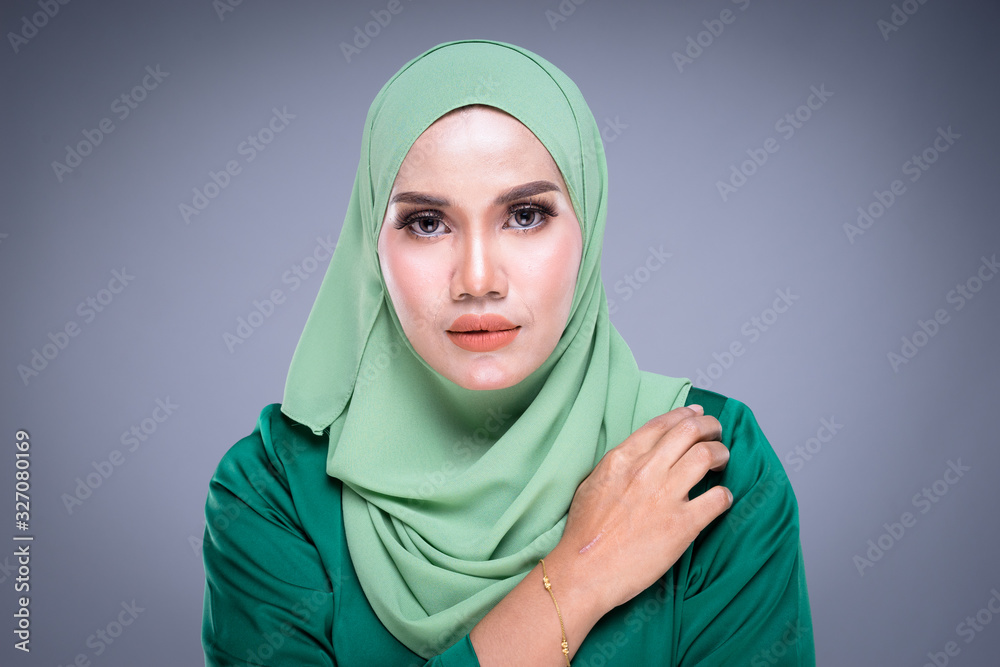 Headshot portrait of a beautiful female Muslim model in modern kurung and hijab, an urban lifestyle apparel for Muslim women isolated on grey background. Beauty and hijab fashion concept. Headshot portrait of a beautiful female Muslim model in modern kurung and hijab, an urban lifestyle apparel for Muslim women isolated on grey background. Beauty and hijab fashion concept.