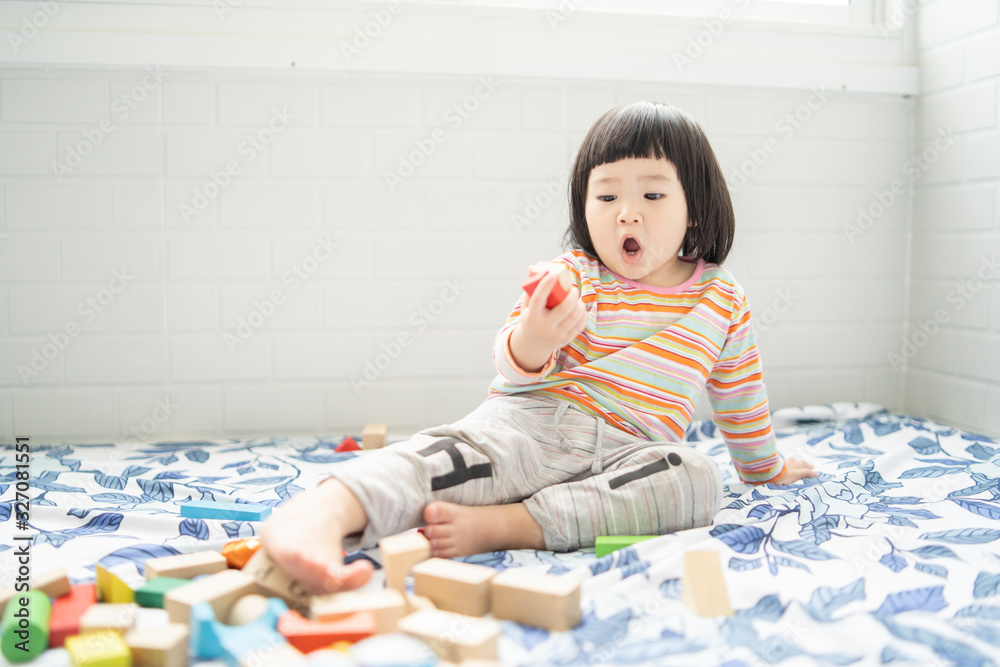 Adorable cute beautiful little Asian baby girl playing with educational wooden toys Healthy happy toddler  colorful wood block indoors at home or nursery, child learning colors  forms family concept