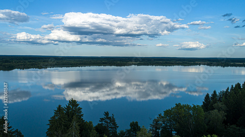 Fototapeta Naklejka Na Ścianę i Meble -  Cumulus clouds reflected in the mirror waters of a lake in sunny weather.