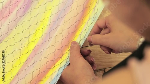 A woman artist works in her studio. Young woman artist knits metal net and working on an art project
