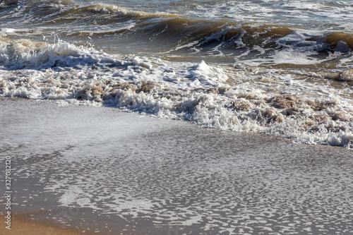 A soft sea wave rolls onto the sand of the beach. Seascape waves on the coast