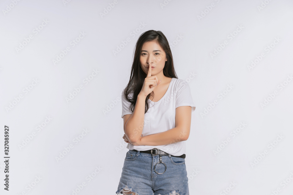 Secret girl. Asian woman saying hush be quiet with a finger on lips gesture isolated on white background t-shirt Short jeans. Copy space Secret girl. Asian woman saying hush be quiet with a finger on lips gesture isolated on white background t-shirt Short jeans. Copy space