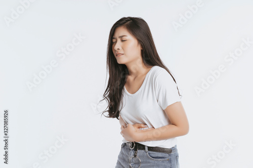 Asian woman unhappy looking sick, suffers from stomach ache stomachache isolated white background because of menstruation and eating spoiled food, Chronic gastritis. Abdomen bloating concept photo