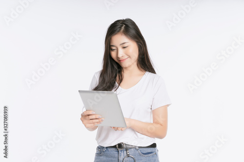 Young beautiful Asian woman in business office standing use tablet in hand, Thai girl enjoy browsing for online shopping store with copy space for advertisement, on isolated white background