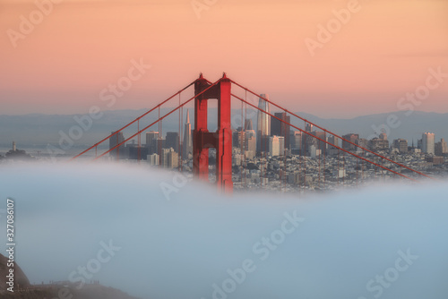 San Francisco rising from fog behind golden gate bridge.