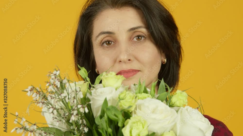 Front view of mature woman holding flowers and looking at camera Front view of mature woman holding flowers and looking at camera