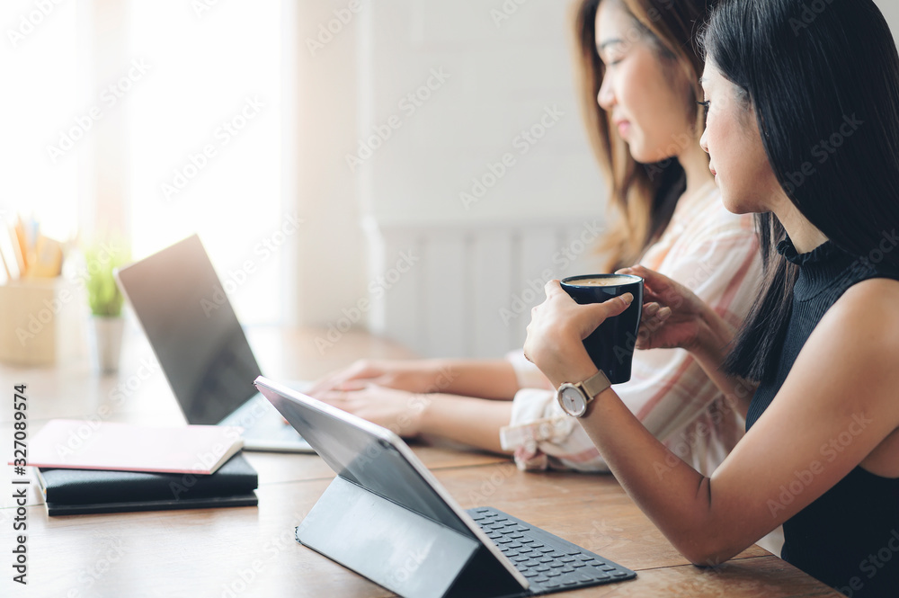 Two young woman working together at co-workspace with sunlight in the morning. Two young woman working together at co-workspace with sunlight in the morning.