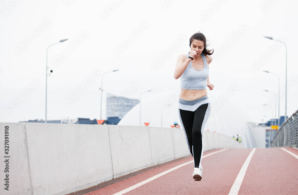 Fototapeta premium Fitness sport girl on intensive evening run, attractive runner jogging outdoors, female jogger in bright sportswear.