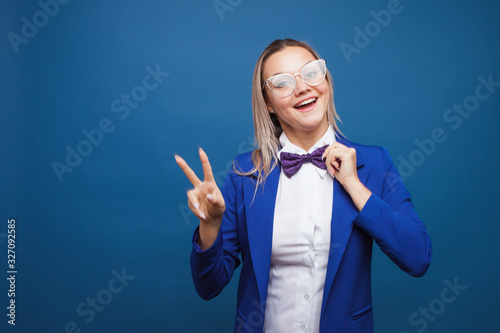 Funny business lady in a blue jacket and purple bow tie. Jumps for joy and shows a victory sign, two thumbs up.