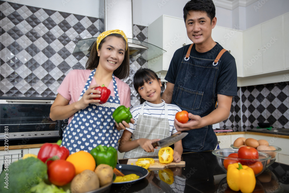 Happy Family have Dad, Mom and their little daughter Cooking Together in the Kitchen Happy Family have Dad, Mom and their little daughter Cooking Together in the Kitchen