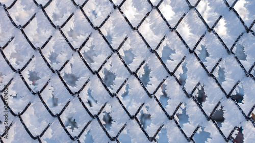 Winter snow texture made of metal mesh covered with snow hoarfrost. Frozen fence