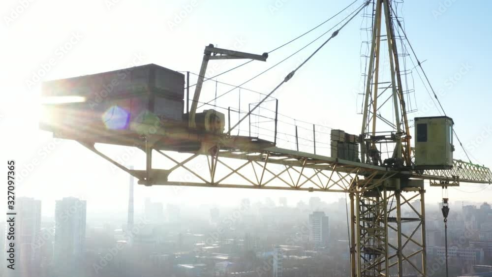 Multi-storey building, tower crane and construction site, top view. At sunset.