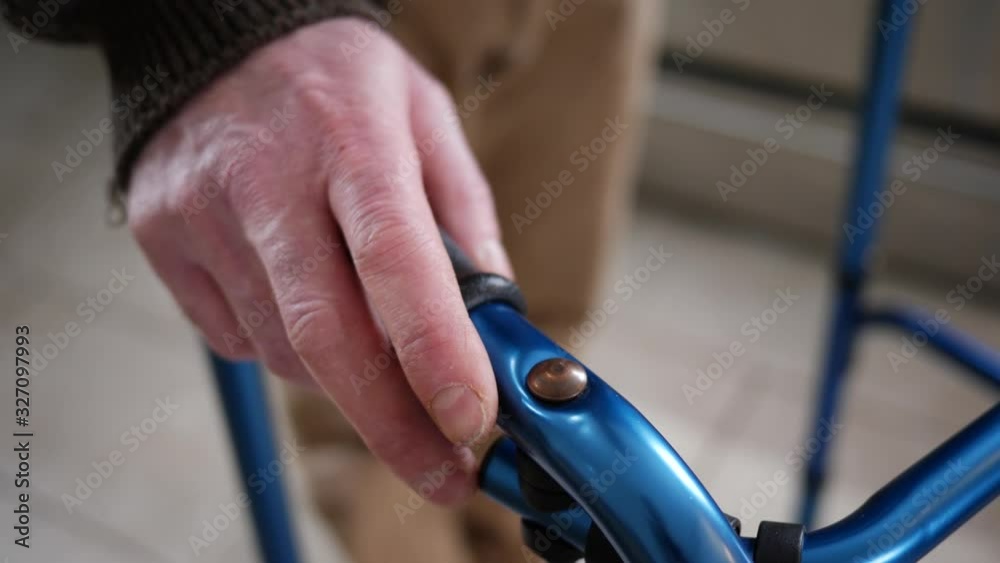 At home, a disabled older man with trembling hands walking with a