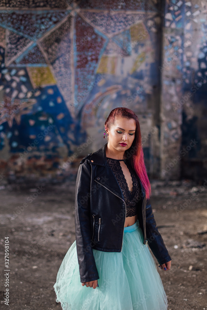 Naklejka premium Portrait of a young girl with pink hair standing inside of collapsed building surrounded by ruins