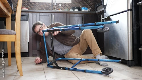 Felt on the ground of his kitchen, a man using a rollator walking frame looking desperate and unable to get back up. He is looking for assistance and help.