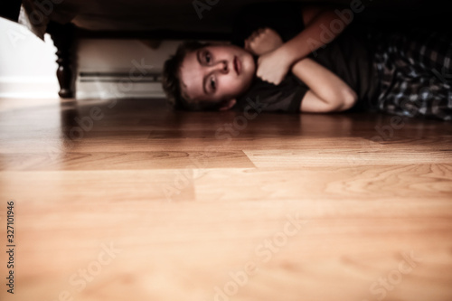 Scared boy hiding under the bed